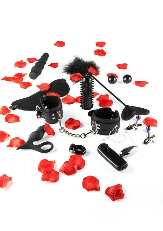 Black BDSM and pleasure sex toy kit with cuffs, vibrator, feather tickler, nipple clamps, and butt plug on white background with red rose petals