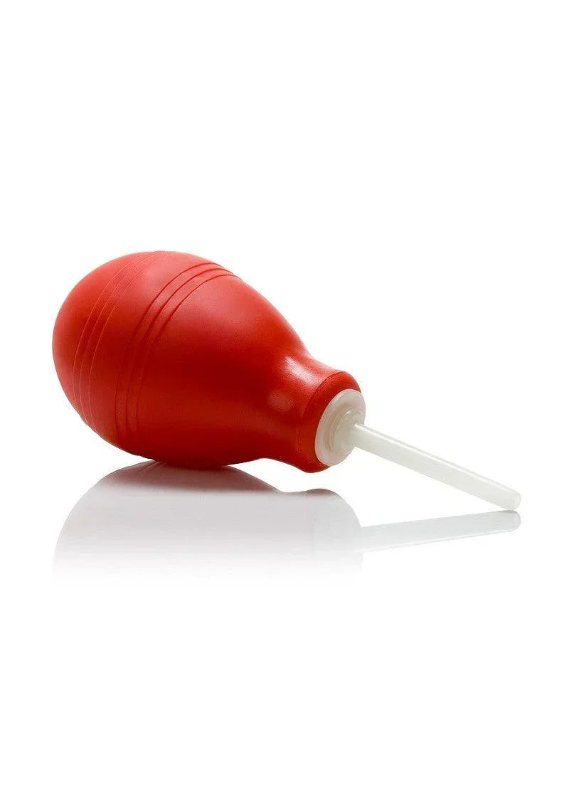 Red anal douche with white applicator tip on reflective white surface, intimate hygiene accessory