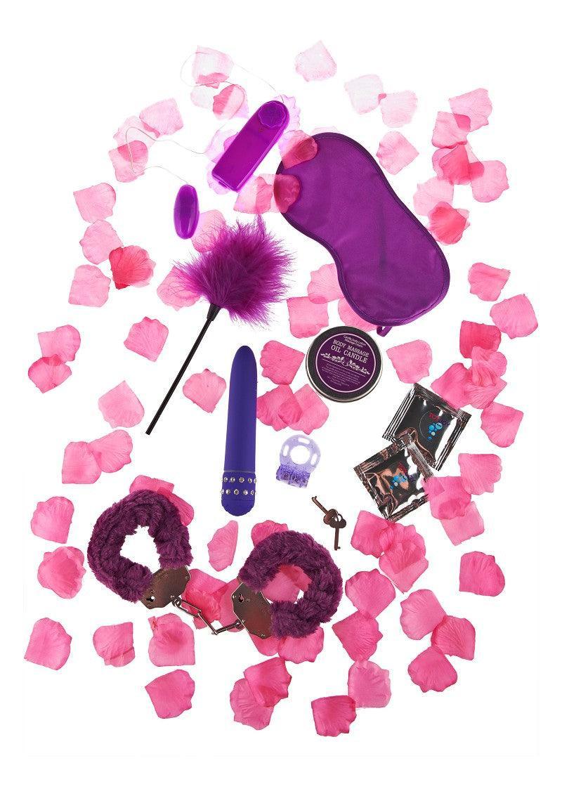Purple-themed adult intimacy kit with vibrator, feather tickler, handcuffs, blindfold, massage candle, condoms, and pink rose petals